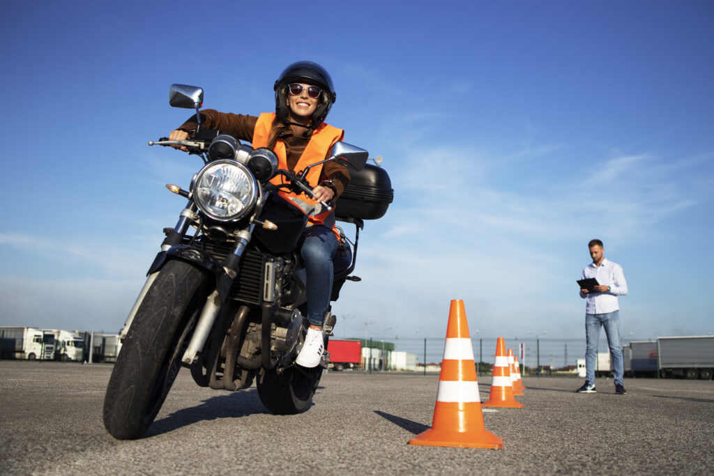 female student with helmet taking motorcycle lessons and practicing ride.